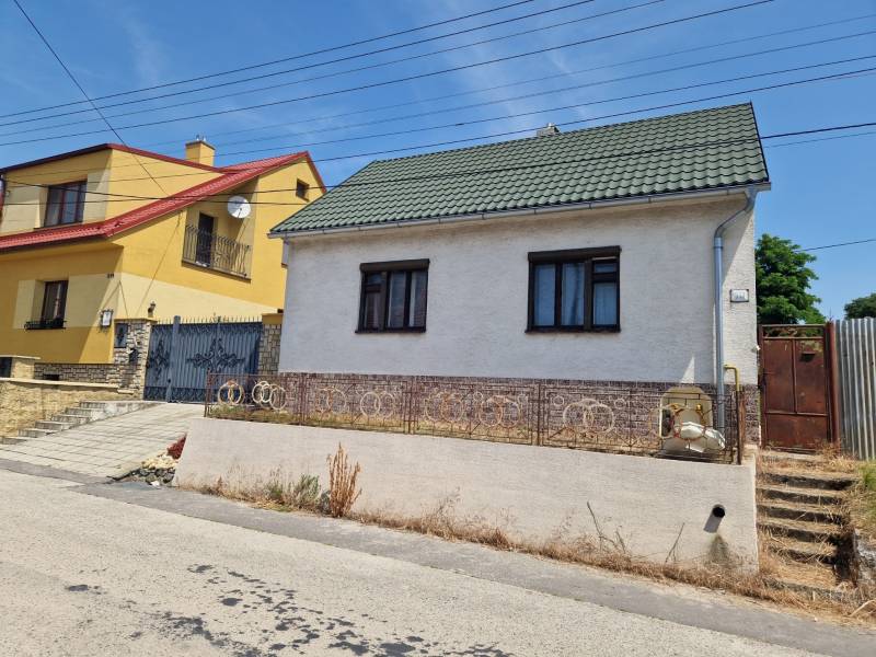 NA PREDAJ RODINNÝ DOM V OBCI ŠTEFANOV, OKRES SENICA - Rodinný dom v Štefanove s bielou omietkou a zelenou strechou na tichej ulici.