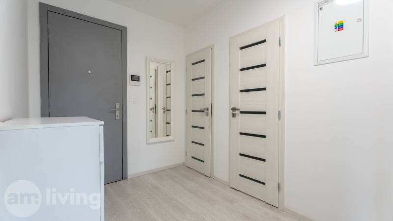 ZARIADENÝ - 3i v novostavbe 76 m2 + balkon - Trenčín - Vstupná chodba v 3-izbovom byte so zrkadlom, bielym nábytkom a svetlými dverami.
