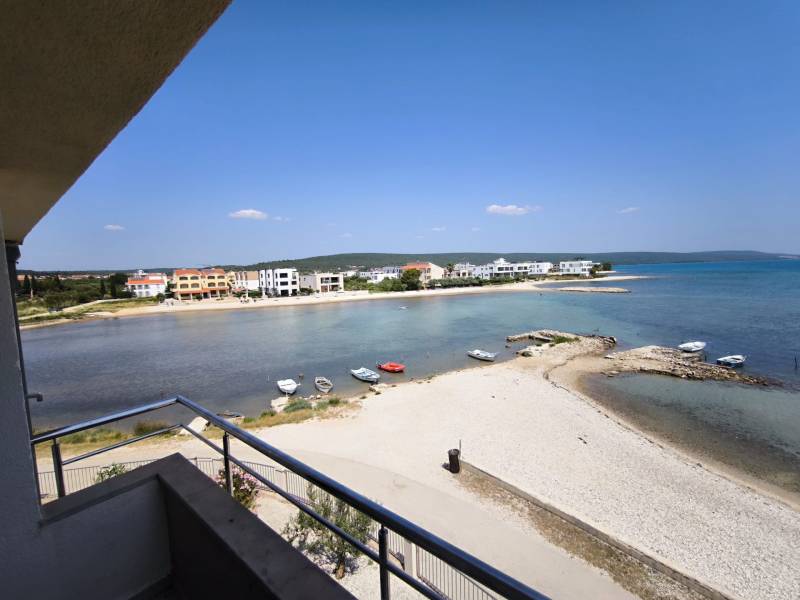 CHORVÁTSKO - Apartmány 1.rad od mora - SUKOŠAN, ZADAR - Výhľad z 1-izbového bytu v Sukošane s plážou a pobrežím na obzore.