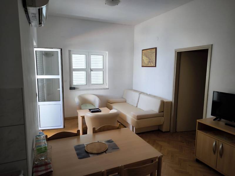 CHORVÁTSKO - Apartmány 1.rad od mora - SUKOŠAN, ZADAR - Jasný 1-izbový byt s drevenou podlahou, stolom, televíziou a sedačkou.