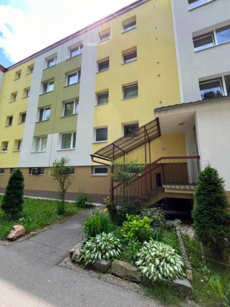 1 izbový byt bauring Tulská PREDAJ  - Bytový dom na Tulskú ulicu v Banskej Bystrici s farebnou fasádou a záhonom.