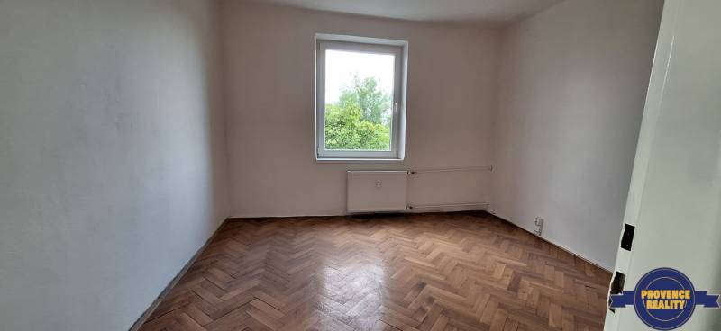 PREDAJ: 3 izbový byt s balkónom, 72 m2 - KOMÁRNO - Prázdna izba v 3-izbovom byte s parketovou podlahou a oknom s výhľadom na zeleň.