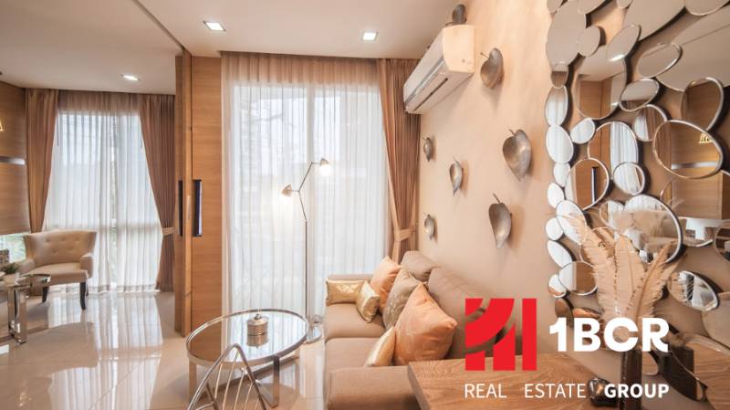 1 IZBOVÝ APARTMÁN A (1 SPÁLŇA + 1 OBÝV. IZBA) CITY GARDEN OLYMPUS  - Obývacia izba 2-izbového bytu so svetlým interiérom, zrkadlami a dekoratívnymi vankúšmi.