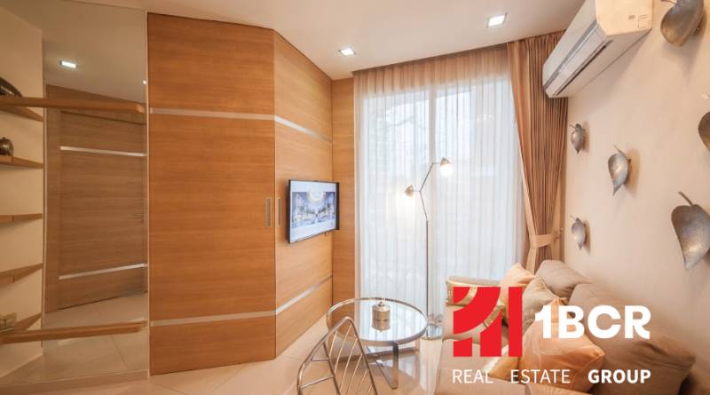 1 IZBOVÝ APARTMÁN A (1 SPÁLŇA + 1 OBÝV. IZBA) CITY GARDEN OLYMPUS  - Obývacia izba v 2-izbovom byte, sedenie, záclony, TV a drevený obklad steny.