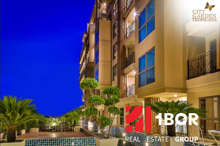 CITY GARDEN TROPICANA PATTAYA - Nočná výstavba bytov v Pattayi s osvetlenými balkónmi a zelenou okolitou výsadbou.
