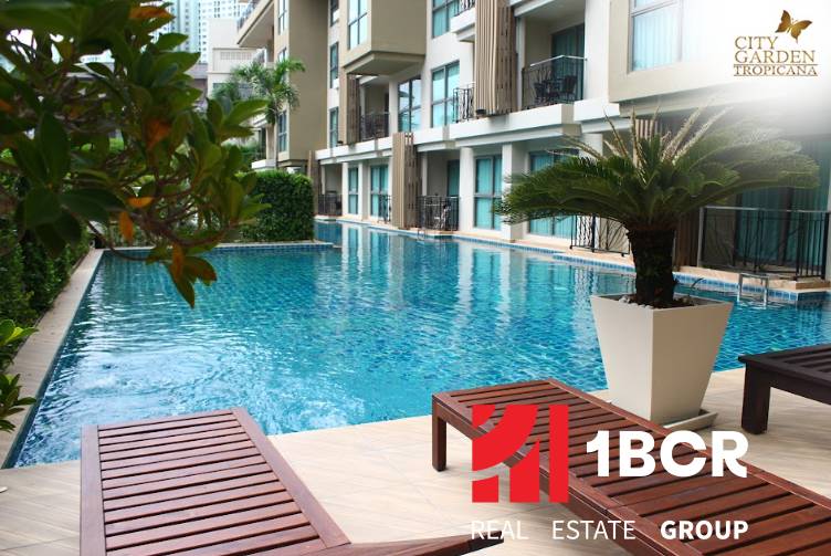 CITY GARDEN TROPICANA PATTAYA - Bazén pri výstavbe bytov v Pattayi obklopený zeleňou a ležadlami.