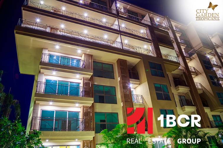 CITY GARDEN TROPICANA PATTAYA - Výstavba bytov v Pattayi s osvetlenou fasádou a množstvom balkónov v noci.