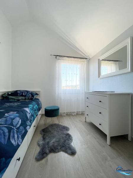 Šolta - nádherný zariadený apartmán s výhľadom na more - Spálňa v rekreačnom apartmáne s posteľou, bielou komodou a kreslom na drevenej podlahe.
