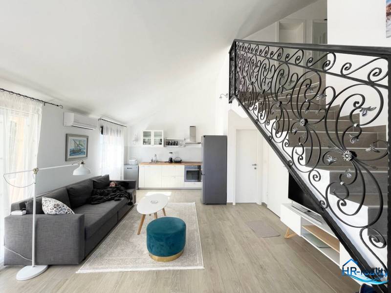 Šolta - nádherný zariadený apartmán s výhľadom na more - Obývací priestor v rekreačnom apartmáne s kuchyňou, sedačkou a schodiskom.