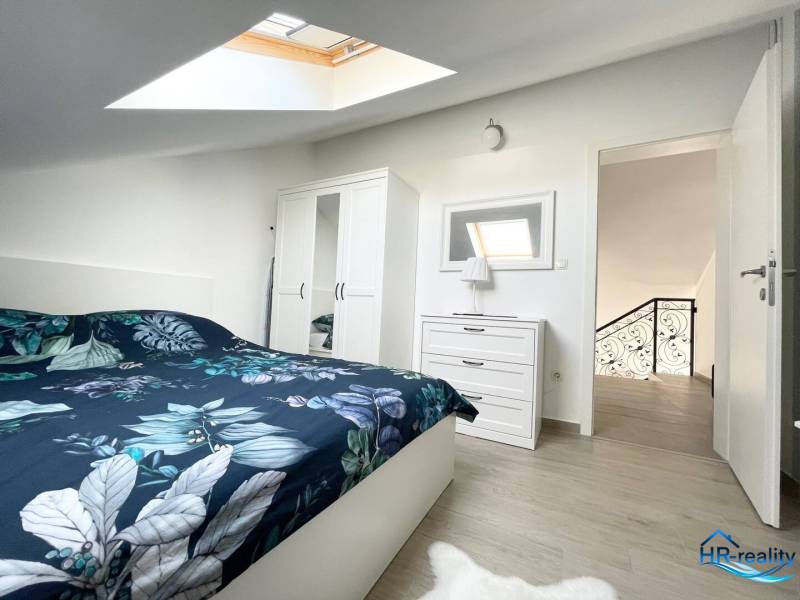 Šolta - nádherný zariadený apartmán s výhľadom na more - Spálňa v rekreačnom apartmáne s posteľou, skriňou a strešným oknom.
