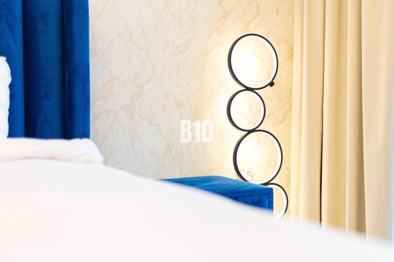 Predaj 3-izbového bytu, Bratislava I - Nástenná lampa s kruhovými rámami pri závesoch v 3-izbovom byte.