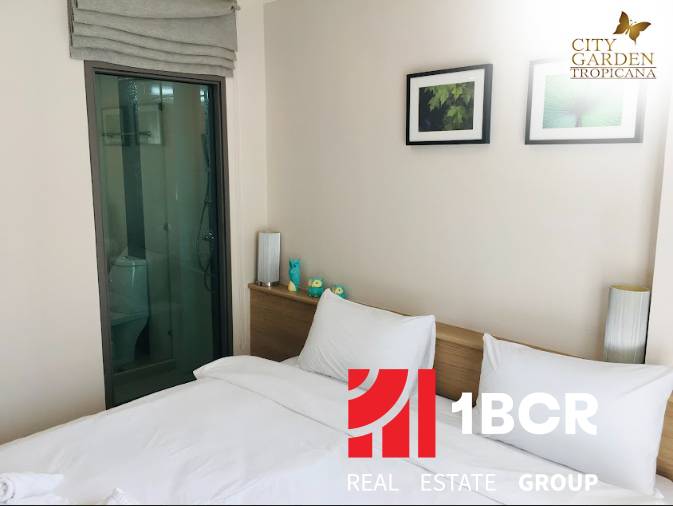 1 IZBOVÝ APARTMÁN (1 SPÁLŇA + 1 OBÝV. IZBA) CITY GARDEN TROPICANA  - Interiér 2-izbového bytu s posteľou, dekoráciou a vstavanou kúpeľňou za sklenenými dverami.