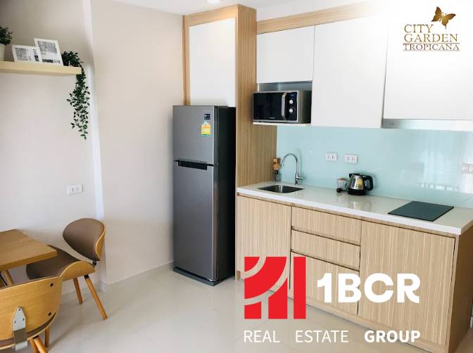 1 IZBOVÝ APARTMÁN (1 SPÁLŇA + 1 OBÝV. IZBA) CITY GARDEN TROPICANA  - Kuchynský kút v 2-izbovom byte s chladničkou, mikrovlnkou a dreveným nábytkom.