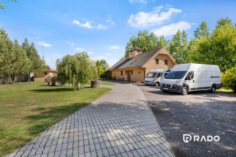 3 nehnuteľnosti na pozemku 4700m2 | Hamuliakovo  - V Hamuliakove na Kostolnej ulici vidno rodinný dom so záhradou a zaparkovanými vozidlami.