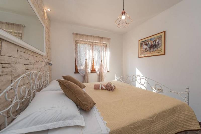 CHORVÁTSKO - Moderný rodinný dom - BIBINJE, ZADAR - Spálňa v rodinnom dome so železnou posteľou, obrazom na stene a kameňovým obkladom.