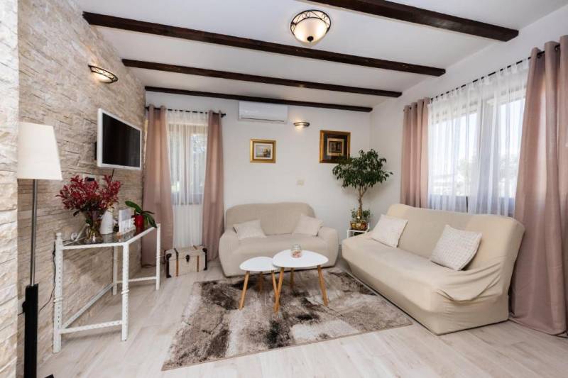 CHORVÁTSKO - Moderný rodinný dom - BIBINJE, ZADAR - Obývacia izba rodinného domu, pohodlné sedačky, TV, zeleň, dekorácie, drevené trámy.