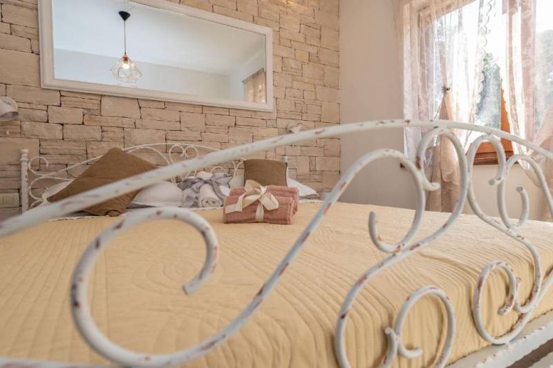 CHORVÁTSKO - Moderný rodinný dom - BIBINJE, ZADAR - Spálňa v rodinnom dome so zdobenou kovovou posteľou a tehlovou stenou.