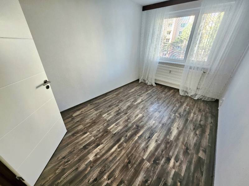 PRENÁJOM 3 IZBOVÝ BYT / 70 M2 /VEĽKOMETRÁŽNY/DUBNIČKA /LOGGIA - Prázdna izba s laminátovou podlahou a veľkým oknom v 3-izbovom byte.