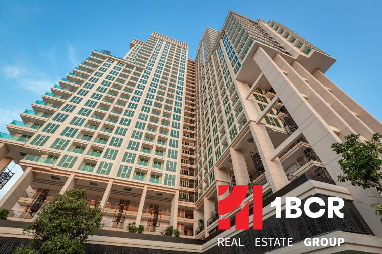 CITY GARDEN TOWER PATTAYA - Výstavba bytov v Pattayi ukazuje vysoké rezidenčné budovy so stromami na pozadí modrej oblohy.