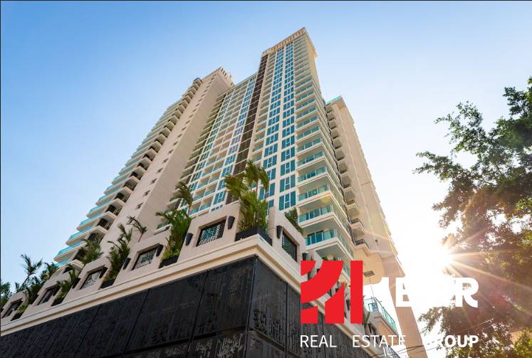 CITY GARDEN TOWER PATTAYA - Výstavba bytov v Pattayi s vysokým mrakodrapom obklopeným palmami a modrou oblohou.