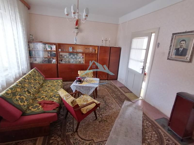 Na predaj rodinný dom v Hrkovciach okres Levice - Obývacia izba v rodinnom dome s retro nábytkom a vzorovanými kobercami.