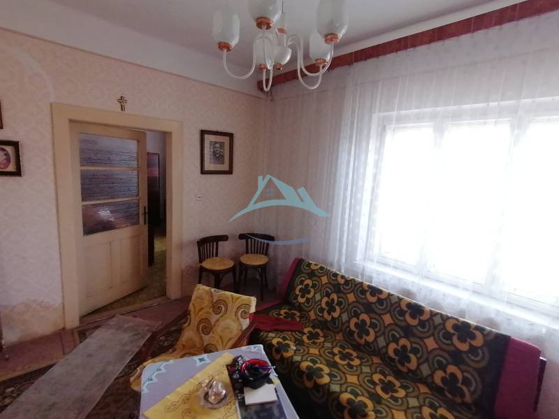 Na predaj rodinný dom v Hrkovciach okres Levice - Izba s vintage sedačkou, nábytkom a záclonami v rodinnom dome.