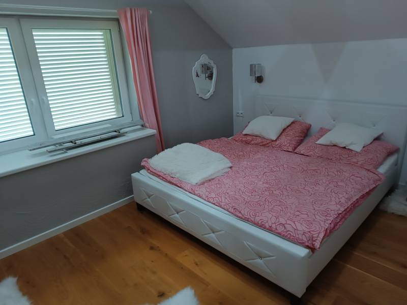 Rekreačná chata Nová Baňa - Drozdovo - Svetlá útulná spálňa s drevenou podlahou a ružovými doplnkami vytvára relaxačnú atmosféru.