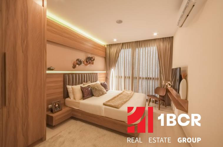2 IZBOVÝ APARTMÁN (2 SPÁLNE + 1 OBÝV. IZBA) CITY GARDEN TOWER PATTAYA - Interiér 3-izbového bytu s elegantnou spálňou, dreveným nábytkom a veľkým oknom s pôsobivými závesmi.