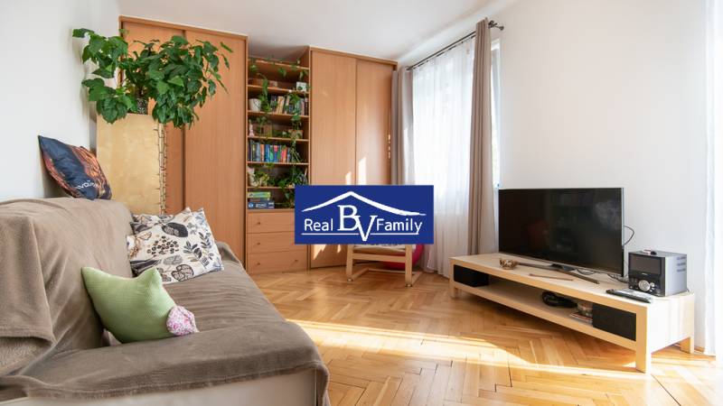 PRENÁJOM, STROMOVÁ, NOVÉ MESTO - DVOJGARSÓNKA - Obývačka v dvojgarsónke so sedačkou, televízorom a veľkou skriňou, svetlé drevené parkety.