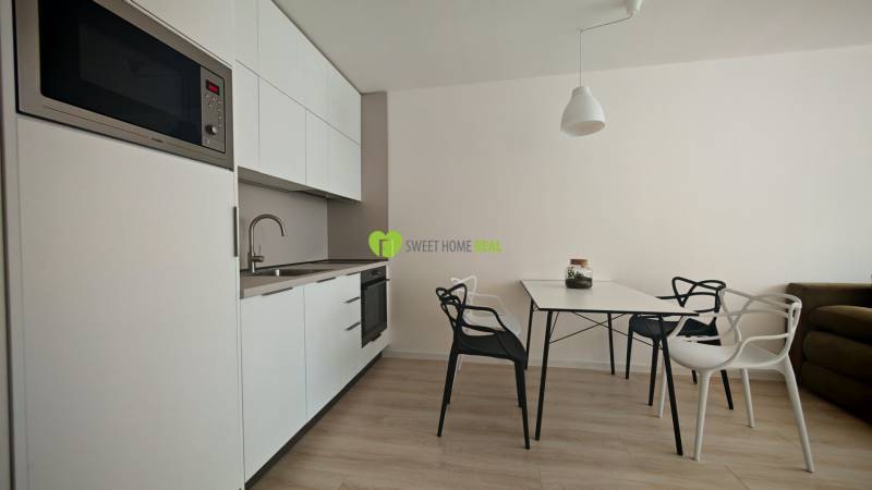 TOP ! na prenájom 1,5i luxusný, klimatizovaný apartmán Košice - Krivá  - Kuchynský kút v 1-izbovom byte, biele skrinky, stôl so stoličkami, drevená podlaha.