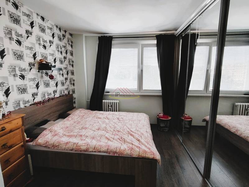 PREDAJ 2 izb. bytu ,52,50 m2, BA - Hornádska ul,2/8.posch., kompl.rek. - Spálňa v 2-izbovom byte s veľkým oknom, posuvnými zrkadlovými dverami a dekoratívnou stenou.