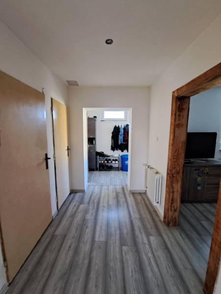 Predáme rodinný dom, pozemok 956 m2, Kmeťovo, okr. Nové Zámky - Chodba v rodinnom dome s laminátovou podlahou, drevenými zárubňami a skladom obuvi.