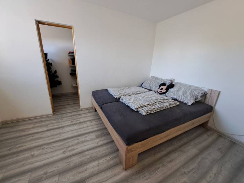 Predáme rodinný dom, pozemok 956 m2, Kmeťovo, okr. Nové Zámky - Spálňa rodinného domu s posteľou, vínovou podlahou a vchodom do komory.