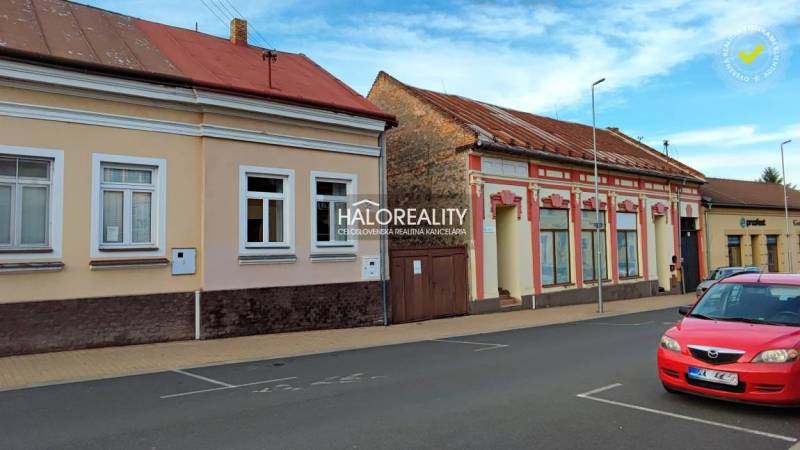 REZERVOVANÉ - Predaj, rodinný dom Lučenec, centrum -... - Rodinný dom v Lučenci so staršími fasádami a zaparkovaným červeným autom na ulici.