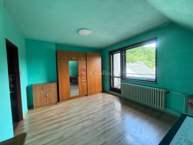 Dvojgeneračný 7i.rodinný dom v Záriečí vhodný na bývanie aj podnikanie - Izba v rodinnom dome s drevenou podlahou, šatníkovou skriňou a balkónovým oknom.