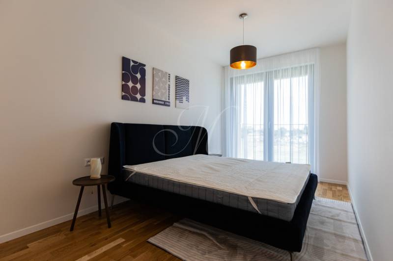 Skvelý slnečný 3i byt s balkónom v projekte METROPOLIS - Spálňa s posteľou a nočným stolíkom, doplnená o dekorácie na stene.