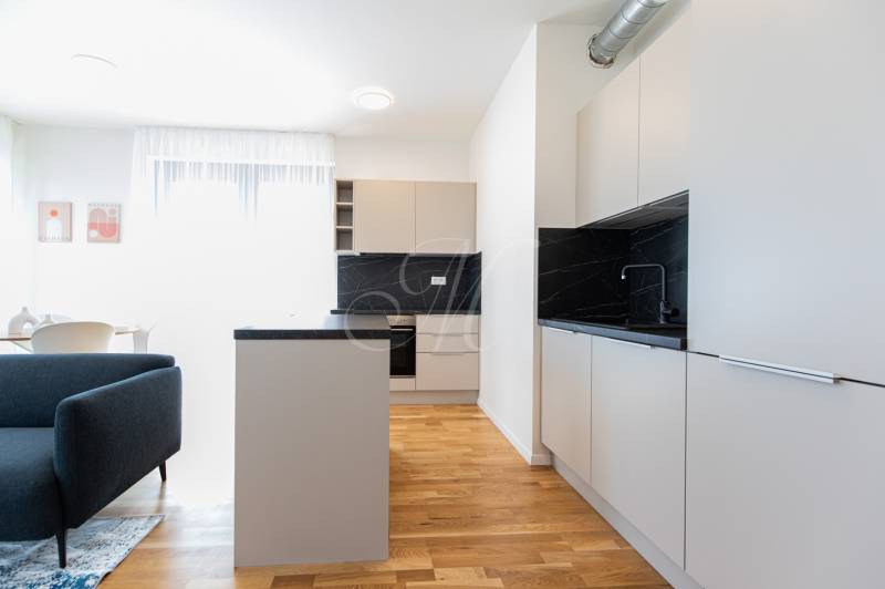 Skvelý slnečný 3i byt s balkónom v projekte METROPOLIS - Kuchyňa v 3-izbovom byte so sivým nábytkom, drevenou podlahou a jedálenským stolom.
