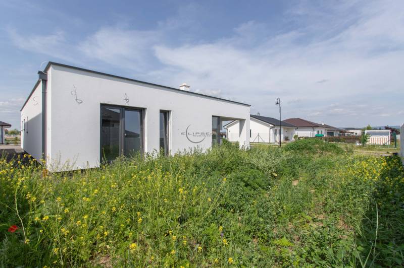 NA PREDAJ NOVOSTAVBA moderný 4-izbový rodinný dom s garážou v Zohore - Rodinný dom v Zohore s rovnou strechou, obklopený záhradou a so susediacimi stavbami.