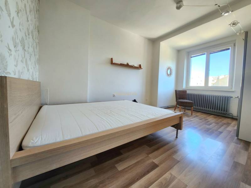 - PRENÁJOM - 2-IZBOVÝ BYT - 61 M2 - OBCHODNÁ UL - STARÉ MESTO - Spálňa v 2-izbovom byte s drevenou podlahou, posteľou a kreslom.