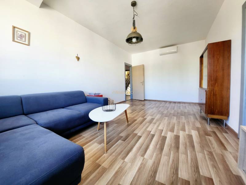 - PRENÁJOM - 2-IZBOVÝ BYT - 61 M2 - OBCHODNÁ UL - STARÉ MESTO - Obývacia izba s modrou pohovkou, drevenou podlahou a minimalistickým nábytkom v 2-izbovom byte.