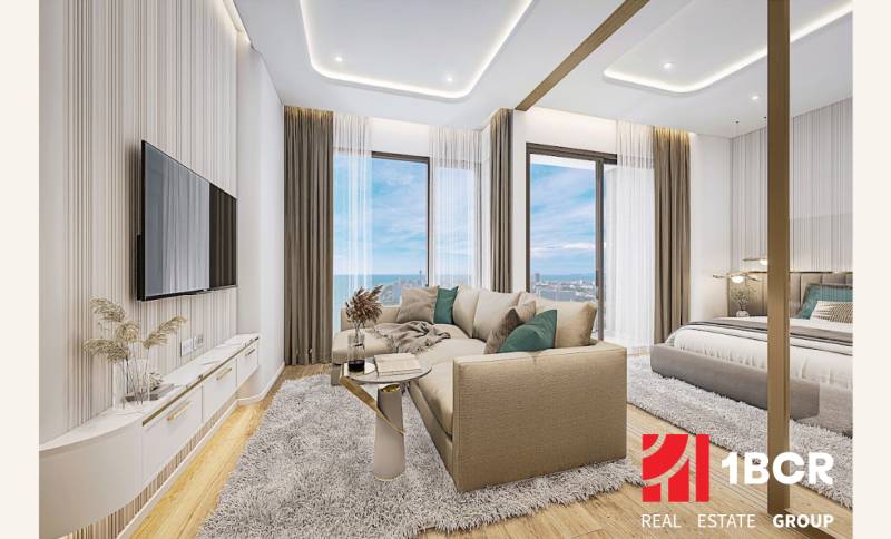 1 IZBOVÝ APARTMÁN (1 SPÁLŇA + 1 OBÝV. IZBA) SEASPIRE JOMTIEN PATTAYA - Obývačka 2-izbového bytu s výhľadom na more, s pohodlným gaučom a televíziou.