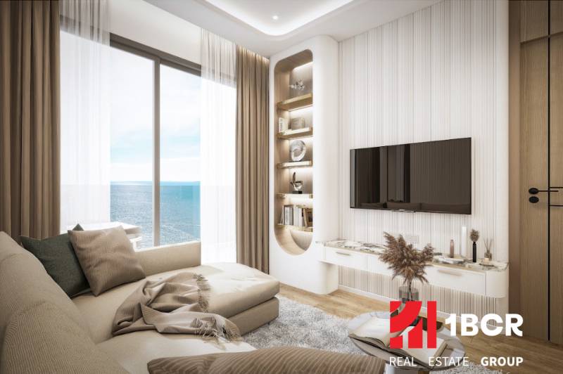 2 IZBOVÝ APARTMÁN (2 SPÁLNE + 1 OBÝV. IZBA) SEASPIRE JOMTIEN PATTAYA - Obývačka v 3-izbovom byte s výhľadom na more, pohodlná sedačka, televízor na stene.
