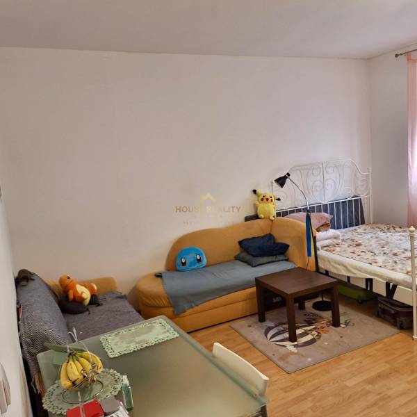 Predaj 1 izbový byt, Karpatská ulica, Bratislava I. Staré Mesto - Izba s pohovkou, posteľou, stolom a plyšovými hračkami v 1-izbovom byte.