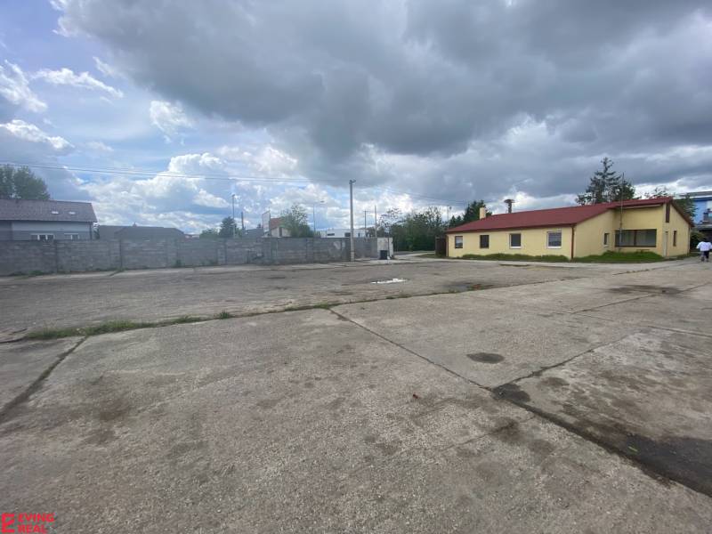 Predaj/prenájom -  areál na  ul. Dvojkrížna, BA - Podunajské Biskupice - Na ulici Dvojkrížna, betónová plocha pri výrobnej budove pod zamračenou oblohou.