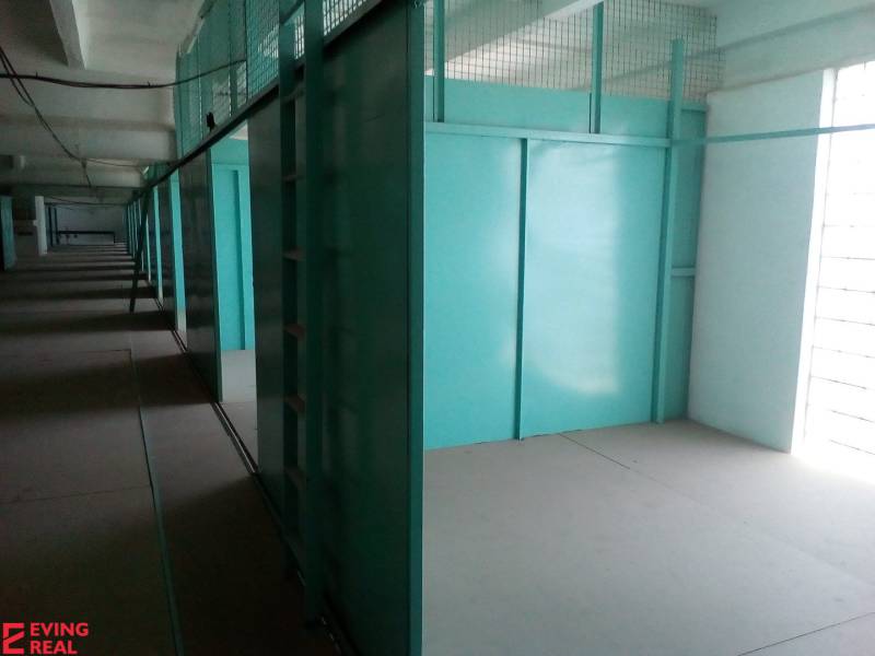 Sklad 16 m2 v stráženom areáli Stará Vajnorská - Chodba na ulici Stará Vajnorská vedľa skladov a hál s modrými kovovými úložnými jednotkami.