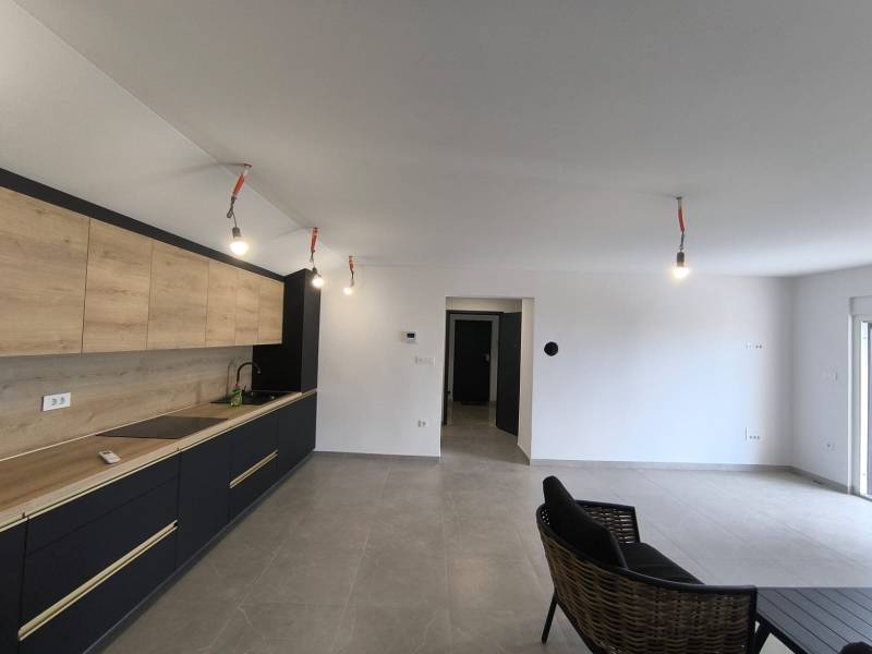 CHORVÁTSKO - Atraktívny apartmán (S6) - Mandre, ostrov Pag - Interiér 4-izbového bytu s minimalistickou kuchyňou a čiernym kreslom v obývačke.