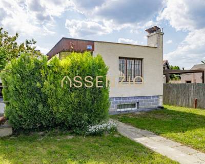 - EXKLUZÍVNE - REKREAČNÝ DOMČEK - ZLATÉ PIESKY  - Rodinný dom na ulici Mokráň záhon v Bratislave-Ružinove, obklopený zeleňou a trávnikom.