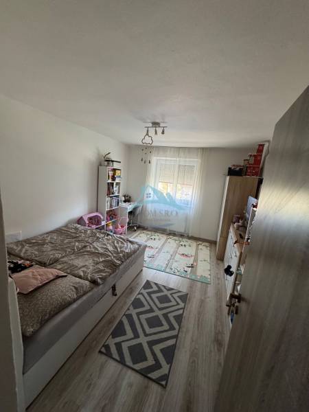 Troj izbový byt na predaj  - Spálňa s posteľou a knihovňou v 3-izbovom byte, svetlá podlaha, dekoratívny koberec.