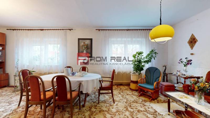 Na PREDAJ rodinný dom vo výbornej lokalite Bratislava - Ružinov - Obývacia izba v rodinnom dome so stolom, stoličkami, dekoráciami a žltým svietidlom na strope.