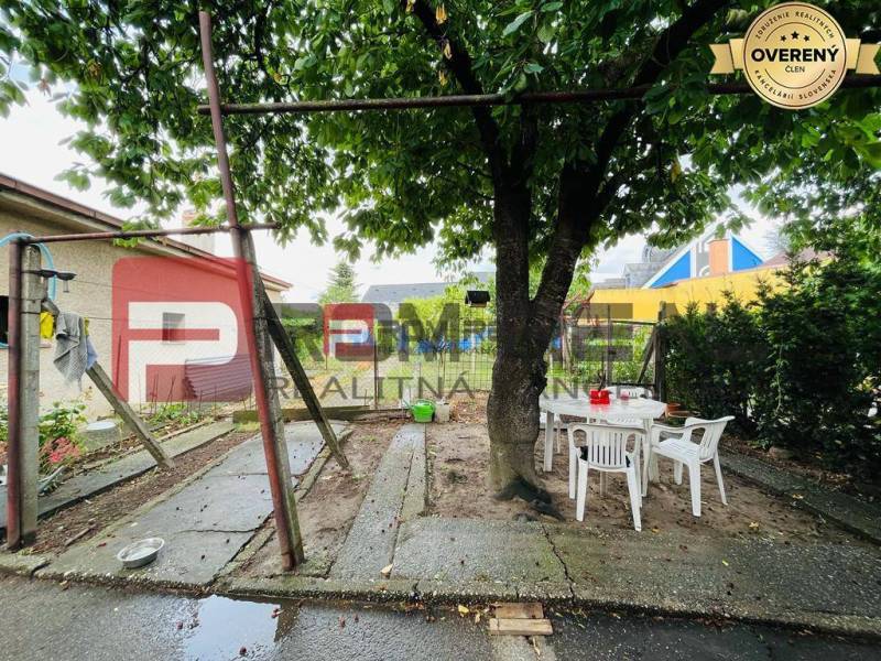Exkluzivne na PREDAJ Rodinný dom Pezinok Nerudová ul. - Rodinný dom na Nerudovej ulici v Pezinku, záhrada so stromom a plastovým nábytkom.